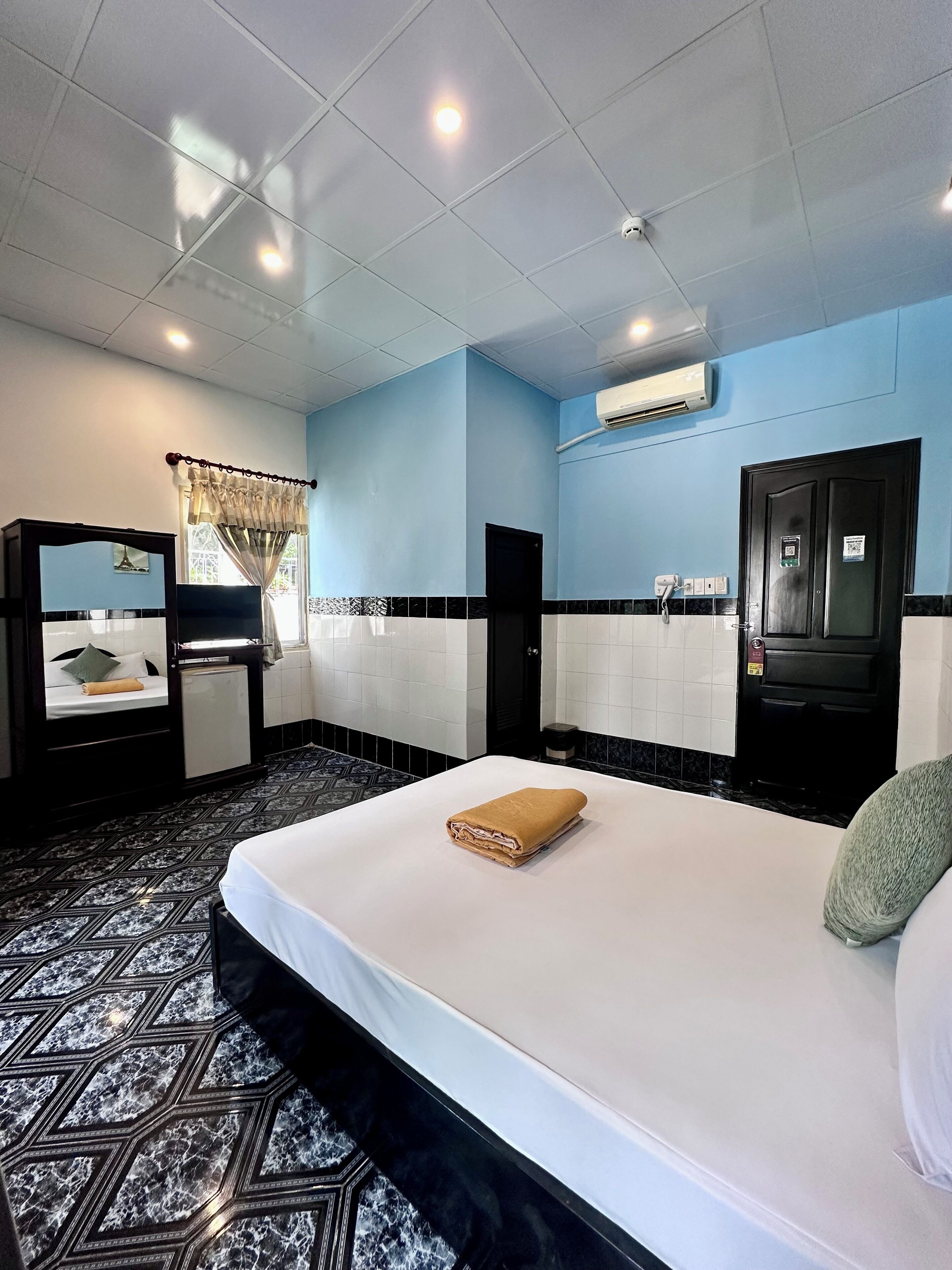 A hotel room with a bed, a desk, a wardrobe, and a window with curtains.