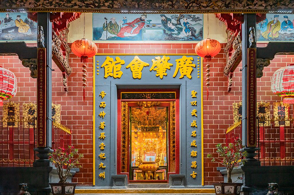 A traditional Chinese temple with a golden entrance, red lanterns, and intricate wall paintings.
