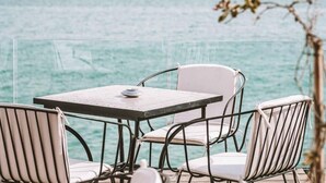 Una mesa y sillas junto a una barandilla de cristal con vista al mar.