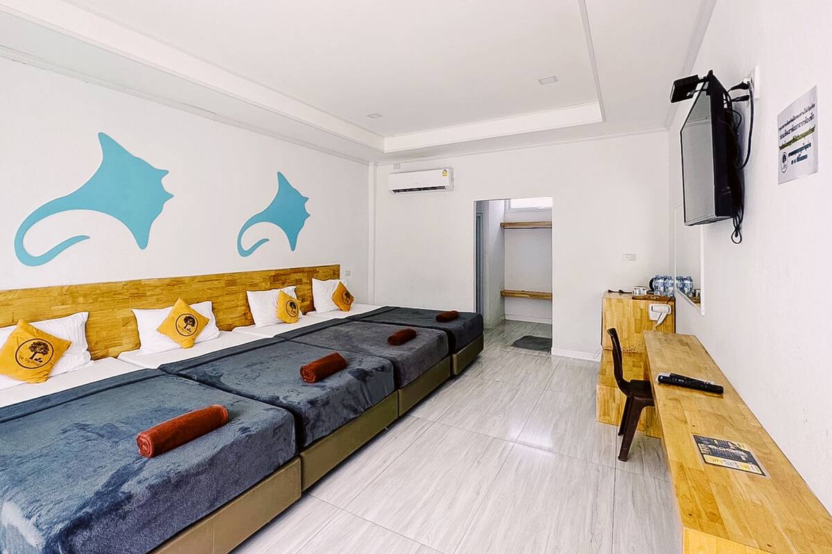 A hotel room with a long bed, a desk, and a TV.