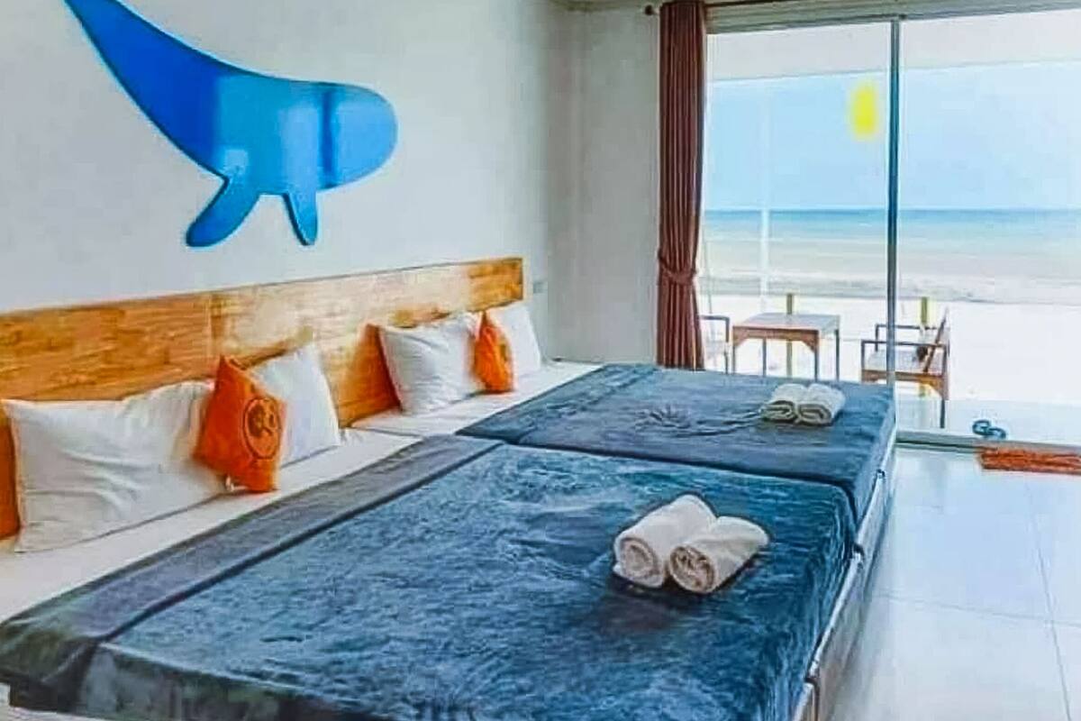 A hotel room with two beds, a wooden headboard, and a view of the beach.