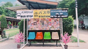 Una parada de autobús con un cartel colorido que anuncia 'The Toy Art Resort'.