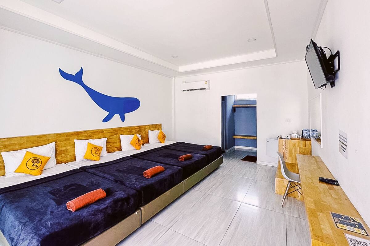 A modern hotel room with a large bed, a wooden headboard, and a blue whale mural on the wall.