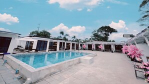 Zona de piscina con cielo azul despejado y nubes.