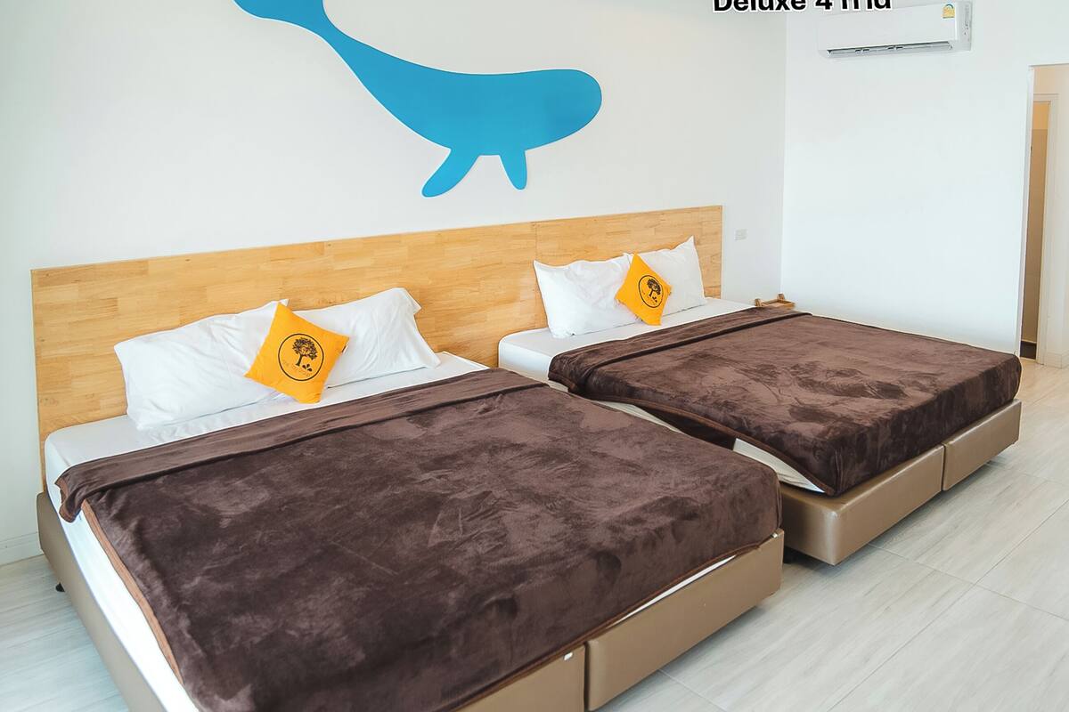 A double room with two beds, each with a brown blanket and a pillow with a yellow logo.
