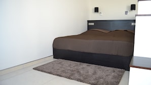 Un dormitorio con una cama, una alfombra pequeña y dos lámparas de pared.