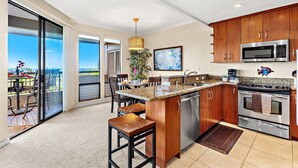 A modern kitchen with a large island, stainless steel appliances, and a view to the outdoors.