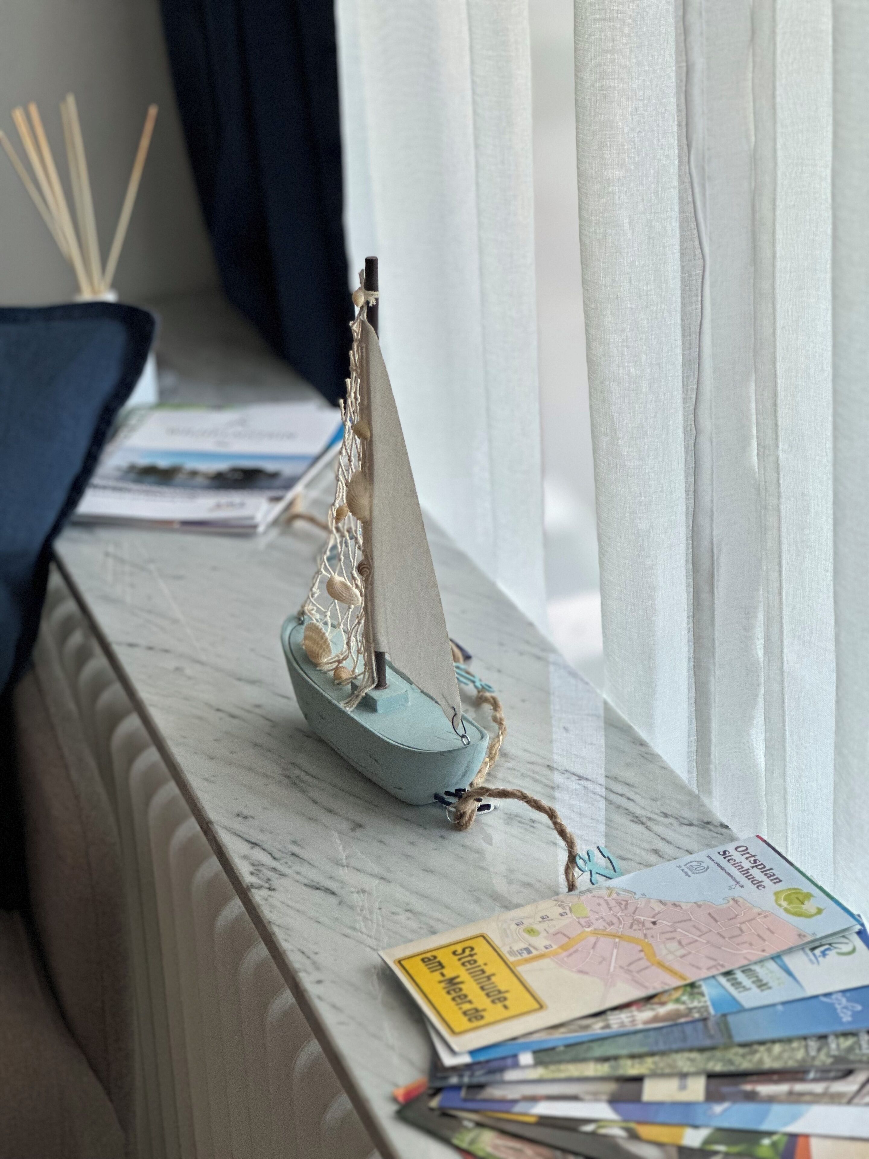 Ein Modellsegelschiff auf einer Marmorstufe zusammen mit einer Karte und Broschüren.