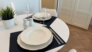 Une table à manger dressée avec des assiettes, des couverts et des verres, agrémentée d’une plante en pot et de salières et de poivrières.
