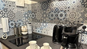 Une cuisine équipée d’une machine à café, de deux tasses et de récipients à café posés sur le comptoir.