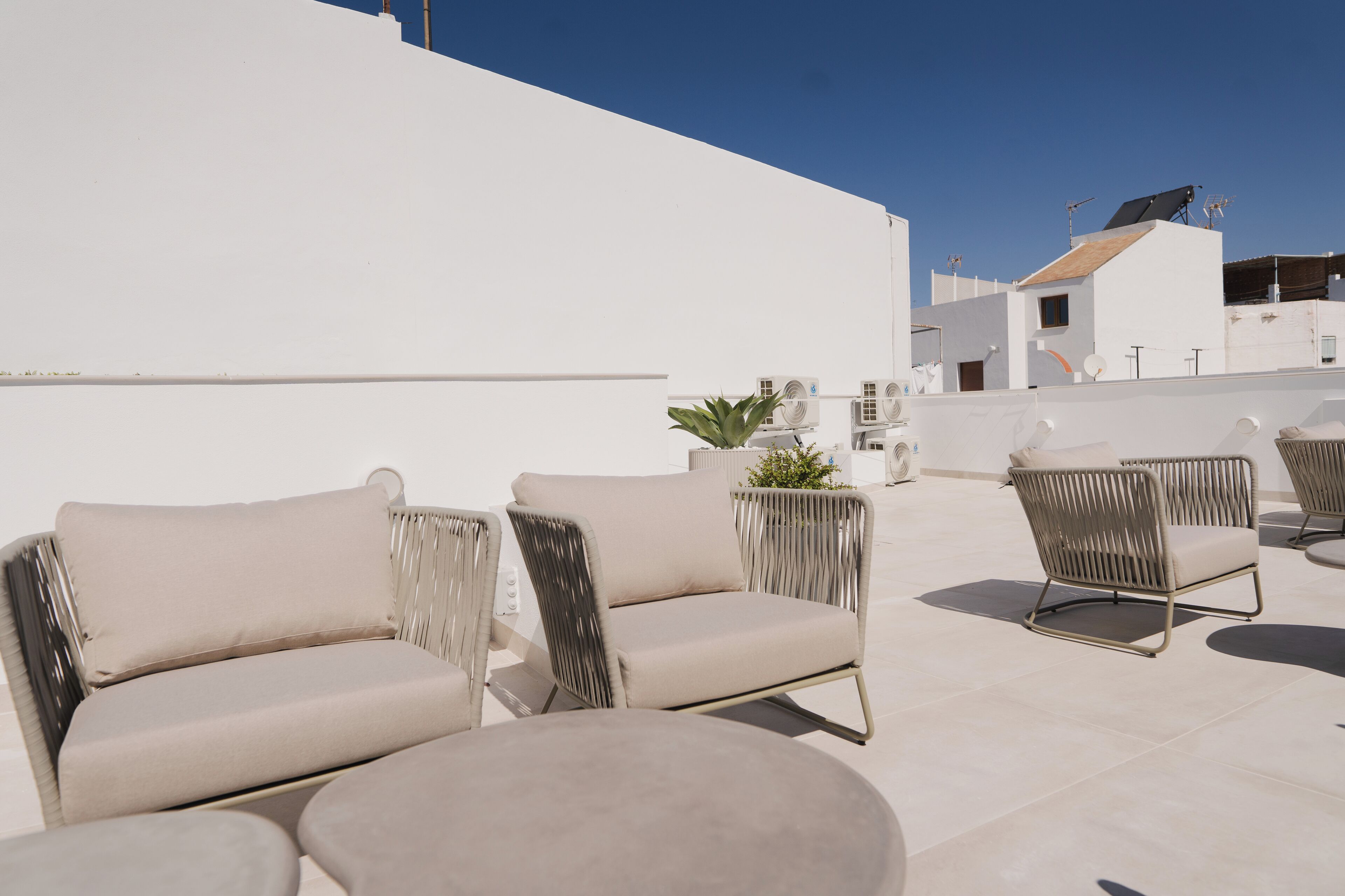 Terraço no telhado com área de estar ao ar livre, incluindo sofás, cadeiras e um vaso com planta.
