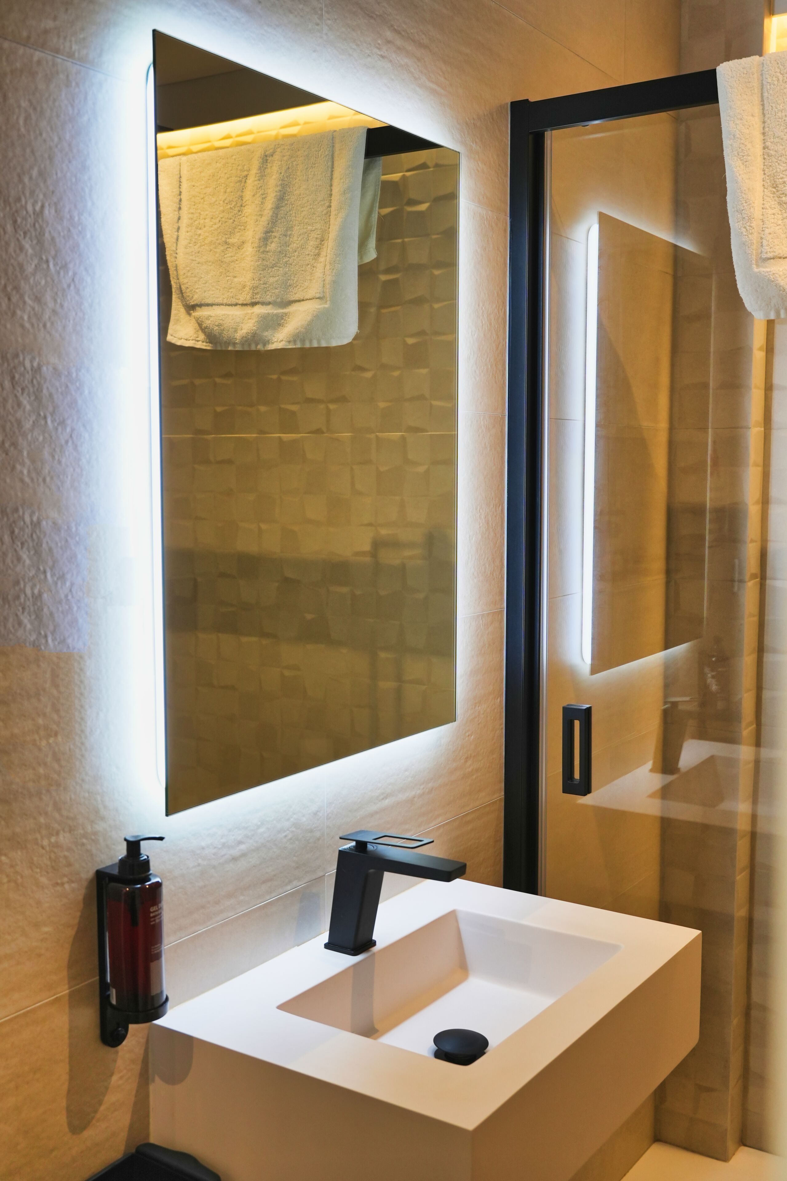A bathroom with a white sink, a mirror, and a towel hanging on the door.