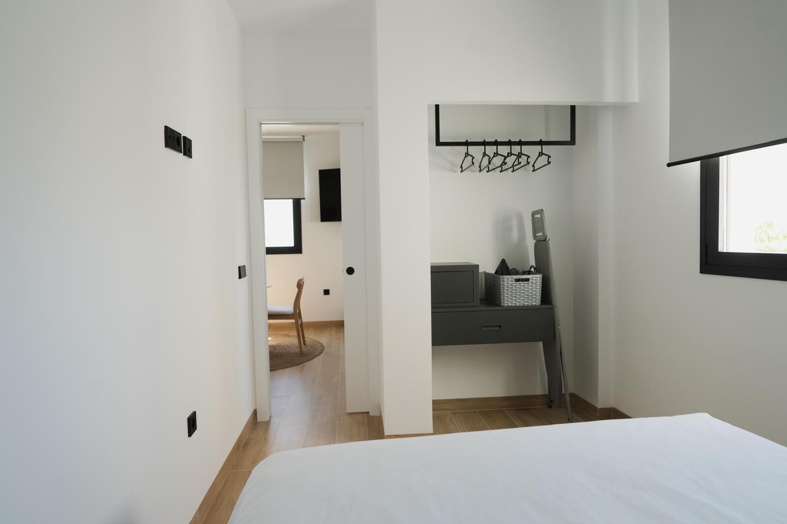Ein modernes Schlafzimmer mit einem großen Bett, einem Schreibtisch mit Stuhl und einem Fenster.