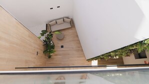 Un intérieur moderne avec un plancher en bois, un canapé, une petite table et une plante en pot.
