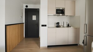 Une cuisine moderne avec des meubles blancs, un four à micro-ondes, une machine à café et un réfrigérateur.