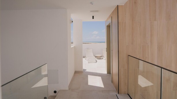 Un intérieur moderne avec une balustrade en verre, une vue sur la plage et un mur en bois.