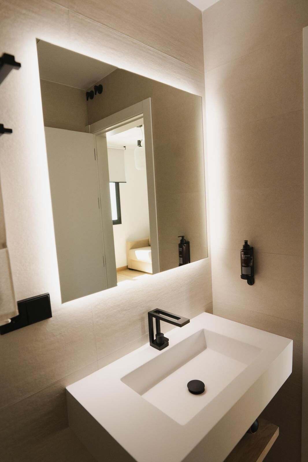 A modern bathroom with a large mirror, a white sink, and a minimalist design.
