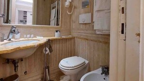 Ein Badezimmer mit Waschbecken, Toilette, Bidet und einem großen Spiegel.