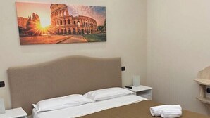 Ein Hotelzimmer mit einem Bett, einem Nachttisch, einer Bank und einem Gemälde des Kolosseums.