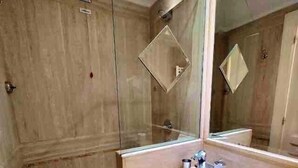 A bathroom with a large mirror, a sink, and a shower area.