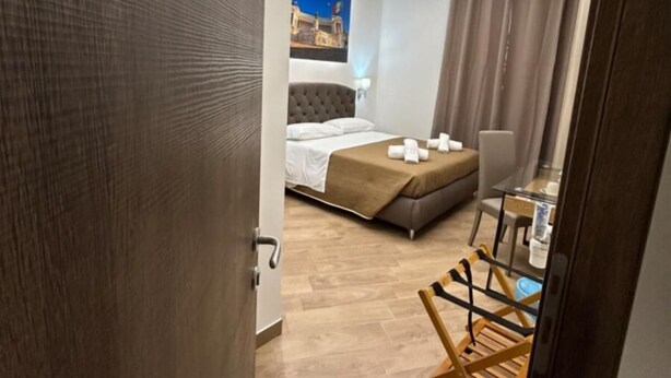 A modern hotel room with a large bed, a seating area, and a view of a cityscape. - grimaldi  comfort   1 (ROMA)