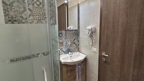 A modern bathroom with a glass shower enclosure, a sink with a mirror, and a wooden door. - grimaldi   comfort   3 (ROMA)