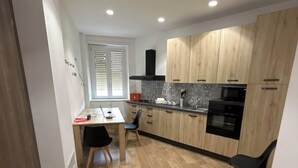 Une cuisine moderne avec des meubles en bois, un micro-ondes noir et un coin repas comprenant une table et des chaises.