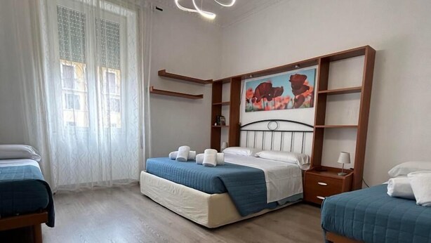 A hotel room with two beds, a large painting, a wooden headboard, and a modern light fixture.