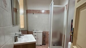 A bathroom with a sink, mirror, and shower.
