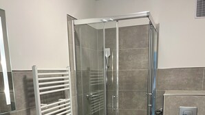 Un baño moderno con ducha de vidrio, lavamanos blanco y retrete.