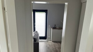 Un pasillo que conduce a una sala de estar con sofá y ventana con persianas.