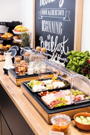 Un bufé con diversas opciones de comida, como frutas, quesos y embutidos.