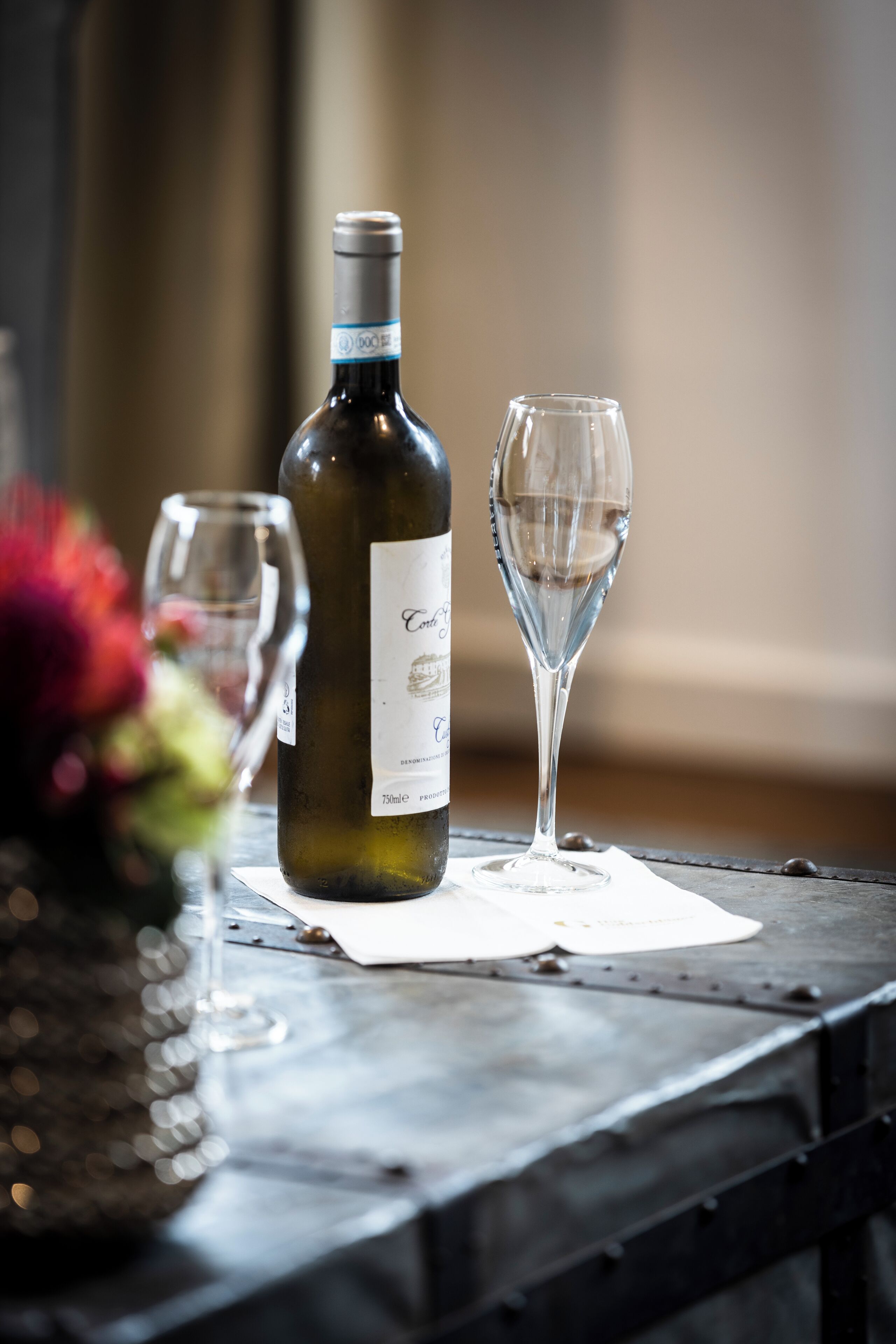A wine bottle and a wine glass on a table with a white paper underneath.