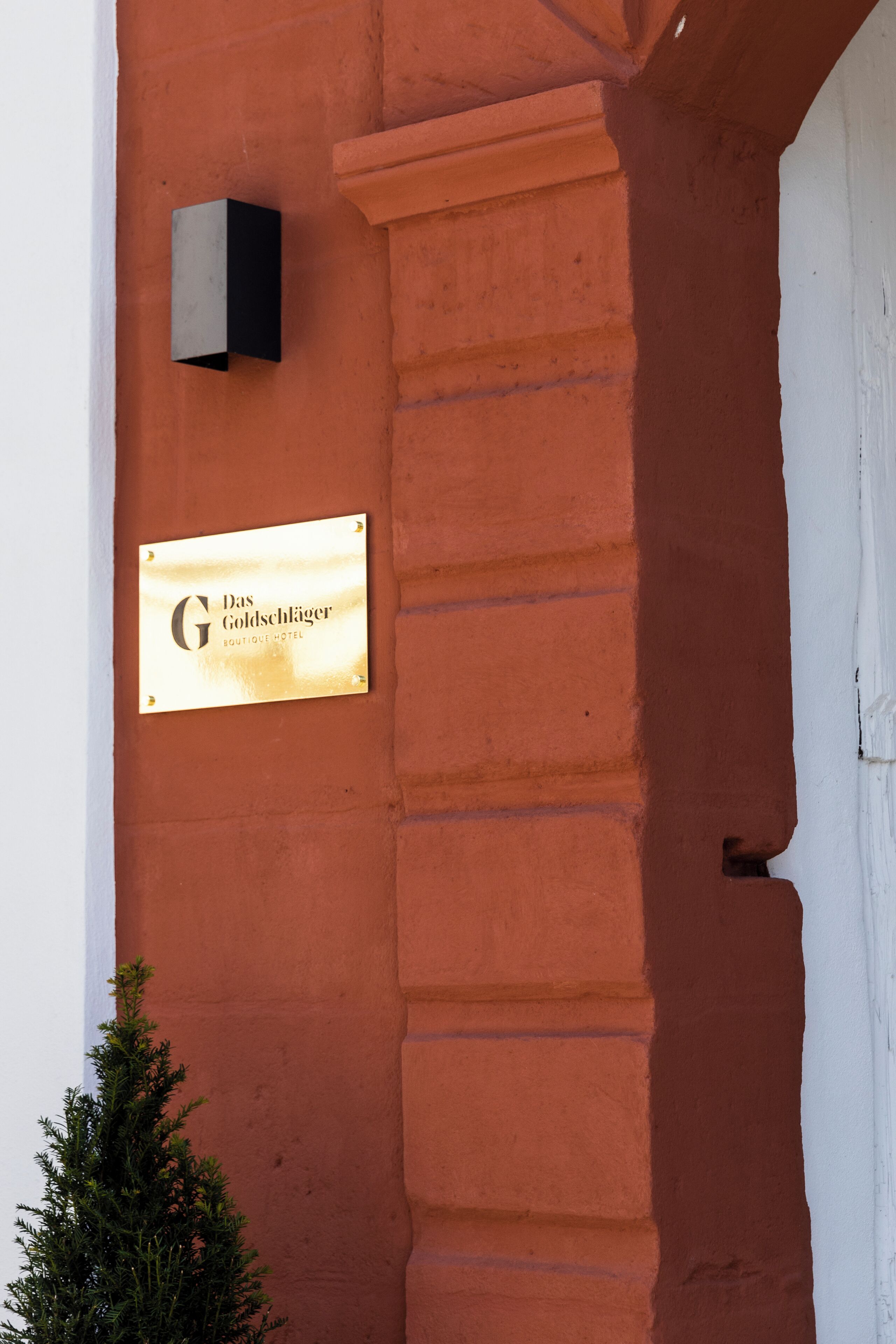Un letrero de hotel sobre un muro rojo con una puerta blanca.