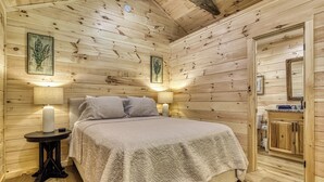 A wooden cabin bedroom with a bed, bedside lamps, and a nightstand. - Stary Night- Pickleball Court, Creek, WIFI, budget friendly (Cosby)