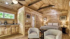 A wooden cabin interior with a kitchen, two armchairs, a bed, and a small table. - Grey Goose, Pickleball Court, Mountain Views, Starting at $69! (Cosby)