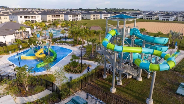 Ein Wasserpark mit mehreren Rutschen und einem Pool, umgeben von Wohngebäuden.
