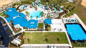 An aerial view of a resort with a large central pool, multiple smaller pools, a basketball court, and a parking area. - Epic 10BR Star Wars Villa • Theater • Pool (Davenport)