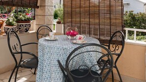 A round table with a patterned tablecloth, black metal chairs, and a potted plant. - Apartments Roda - (Supetar)
