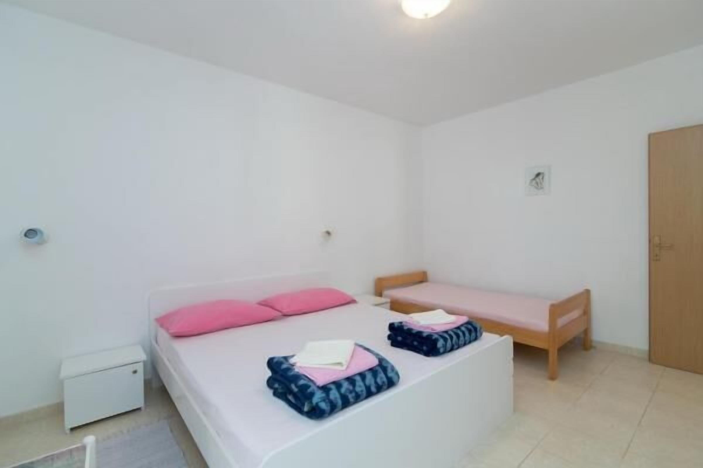 A small, clean room with a single bed, a bedside table, and a wooden wardrobe.