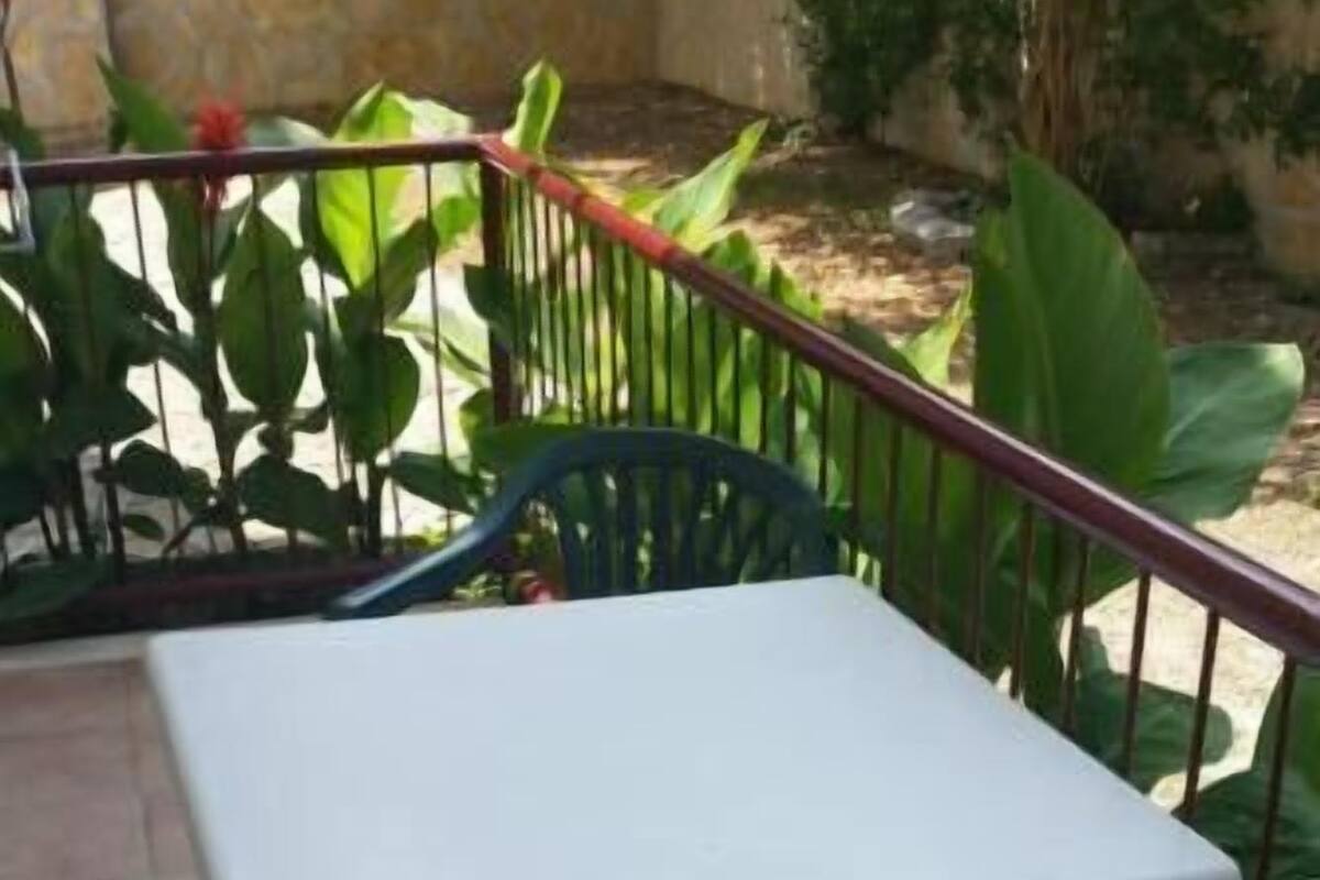 A small outdoor patio with a white table and two blue chairs.