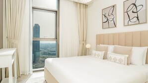 Een moderne hotelkamer met een groot bed, een nachtkastje en uitzicht op een stadsgezicht door een groot raam.