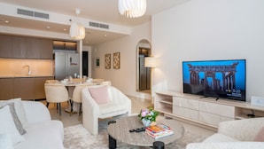 Een moderne woonkamer met een flatscreen televisie, een eethoek en een keuken.