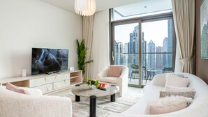 Een moderne woonkamer met een grote televisie, comfortabele zithoek, een salontafel en uitzicht over de stad.