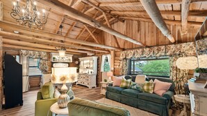 Interior rústico de una cabaña de troncos con una zona de estar acogedora, una cocina y un comedor.