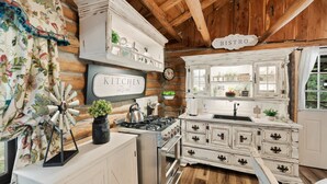 Una cocina rústica con vigas de madera, una estufa blanca y un cartel que dice 'KITCHEN let's eat'.