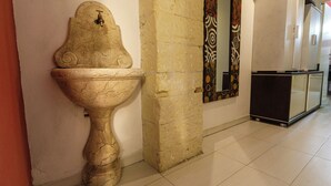 Une salle de bain avec un lavabo en pierre, un miroir et un meuble blanc.