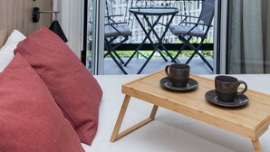 Una habitación moderna con una mesa de madera, dos tazas y un cojín rojo.