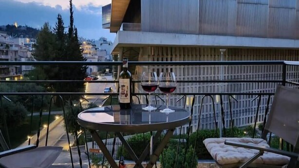 Un balcón con una mesa, dos sillas y una botella de vino.