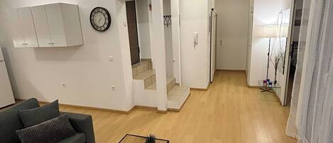 A modern living room with a sofa, coffee table, and a staircase leading to another room.